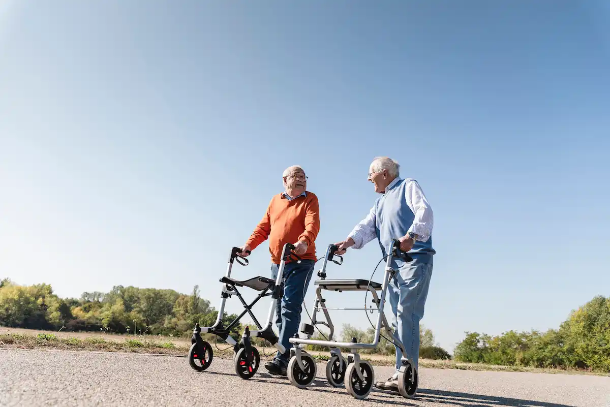 two old friends walking on a country road using wheeled walkers